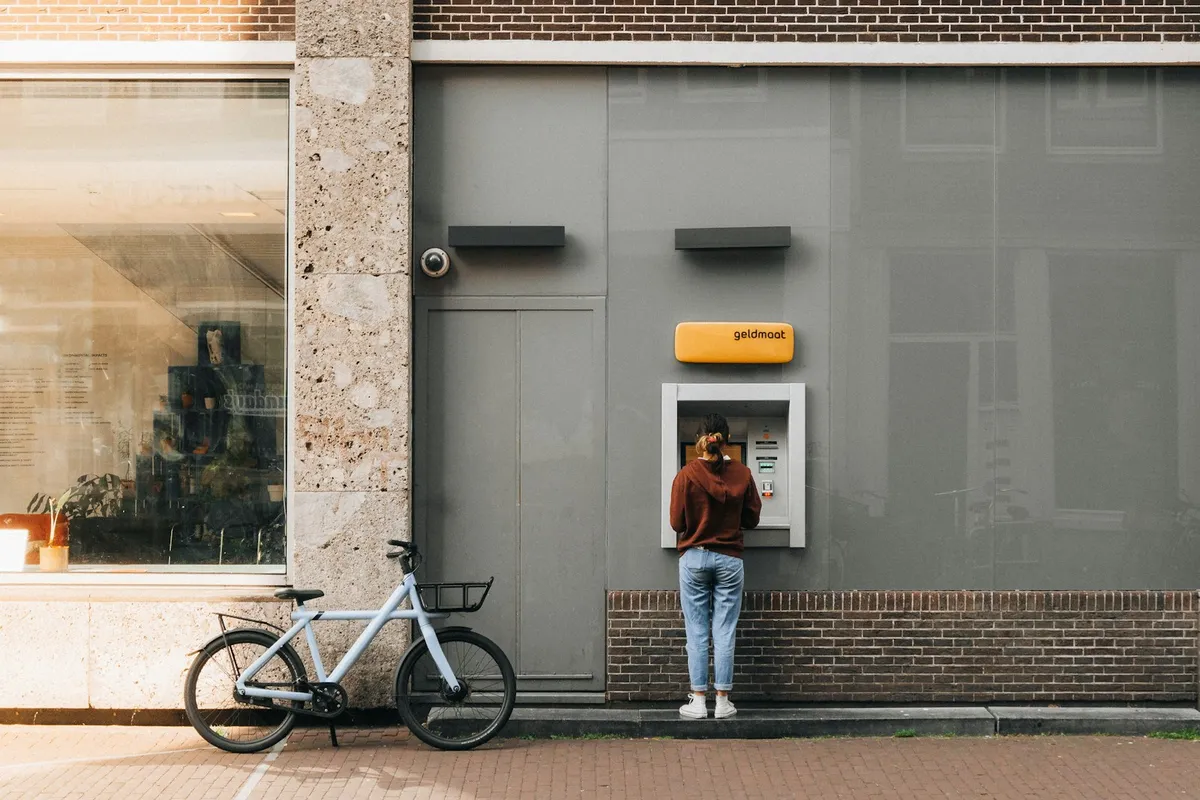 A person standing at an ATM in a bank lobby