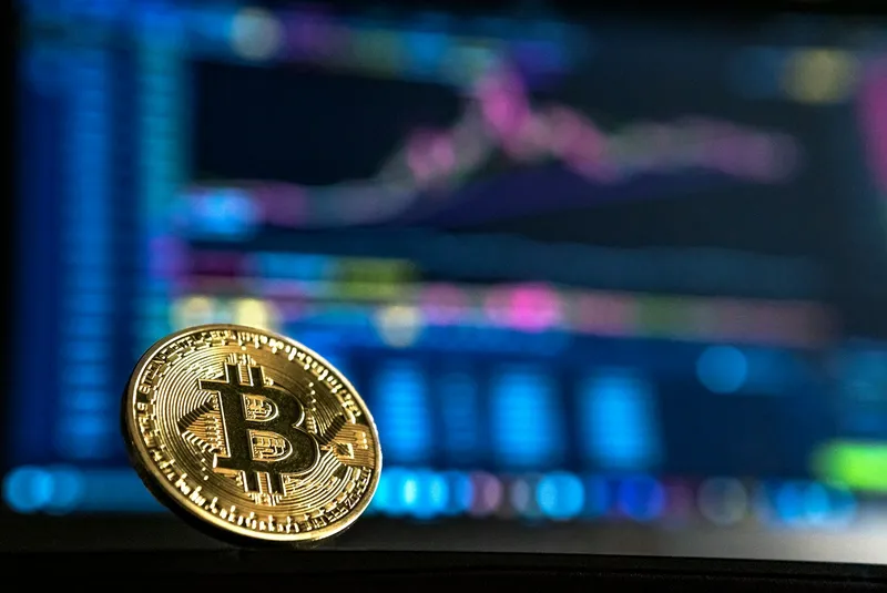 Gold-coloured physical bitcoin coins stacked on a dark surface