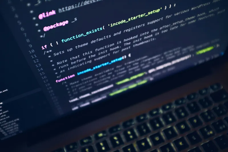 Open laptop showing a dark screen on a wooden desk